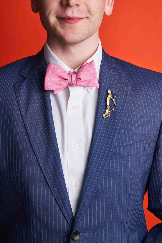 man in blue suit wearing decorative brooch